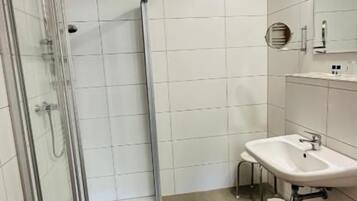 A bathroom with a glass shower enclosure, a sink, and a mirror.
