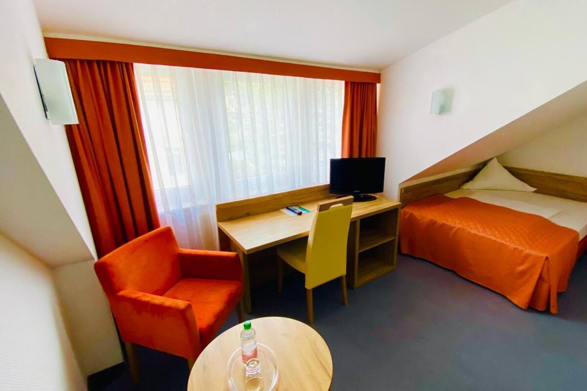 Una habitación de hotel con escritorio, silla, cama y una pequeña mesa.