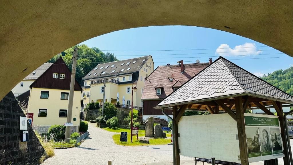 A traditional European village with stone buildings, a paved street, and a wooden gazebo.