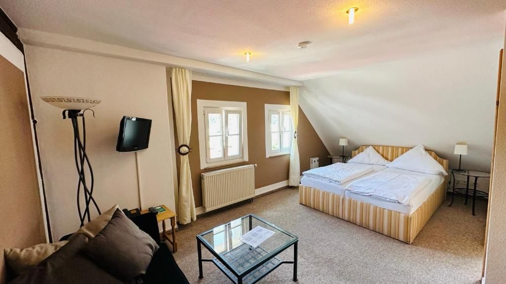 Quarto de hotel com cama, mesa pequena, televisão e radiador.
