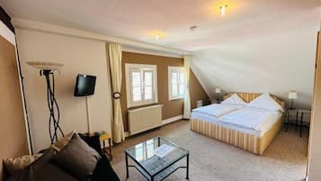 Quarto de hotel com cama, mesa pequena, televisão e radiador.