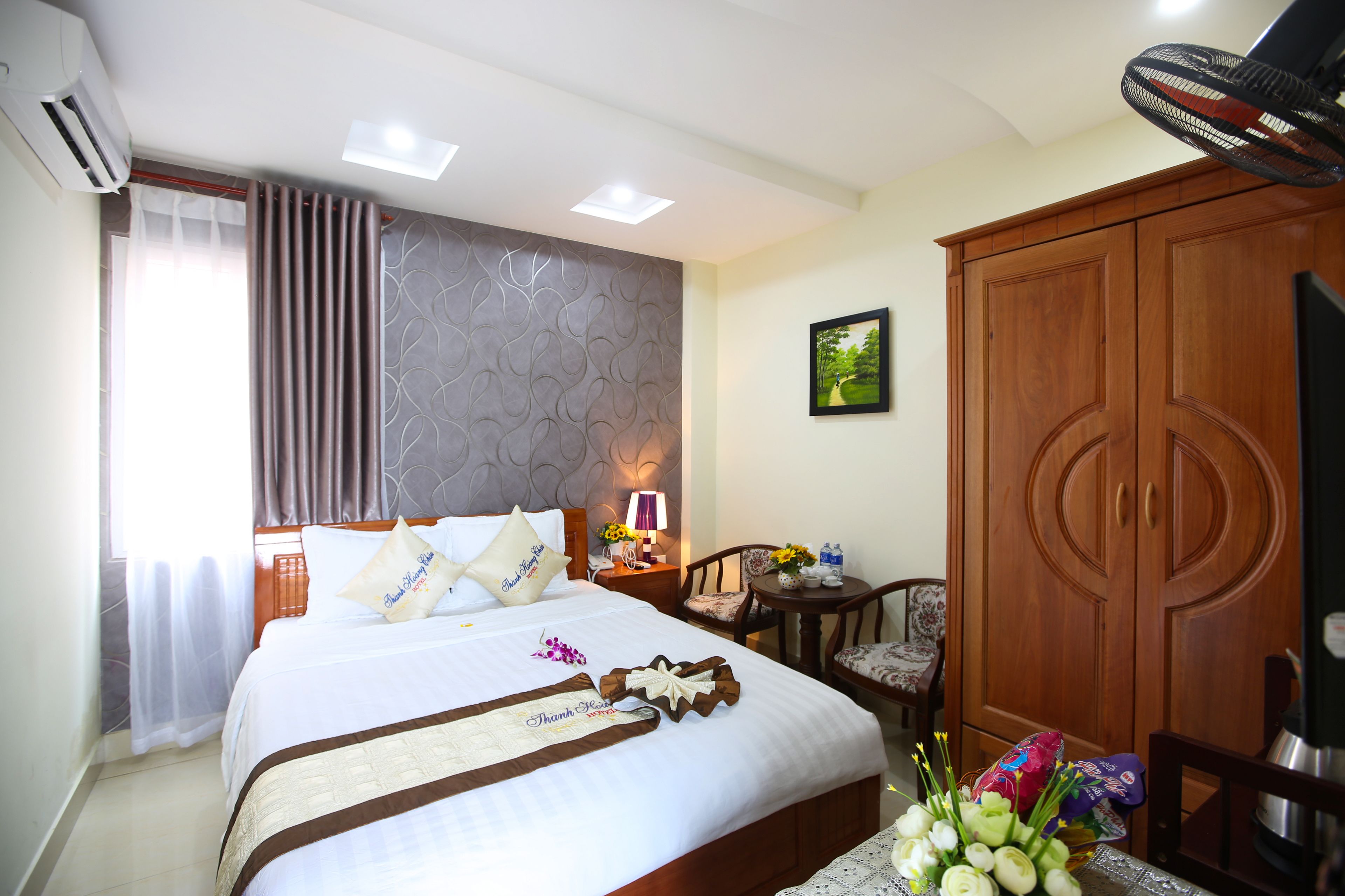 Een hotelkamer met een bed, een houten kledingkast, een bureau met een lamp en een stoel.
