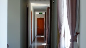 A hotel hallway with a polished floor, wooden doors, and a visible exit sign.