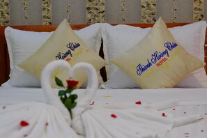 Una cama con dos almohadas, una de ellas con la etiqueta "Thanh Hoa Hotel", y un cisne decorativo de tela.