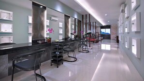 A modern hotel lobby with a long reception desk, multiple chairs, and a large mirror. - Famous Hotel Kuta (Tuban)
