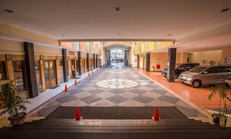 Entrada de hotel con piso a cuadros, una escalera y una fila de coches estacionados.