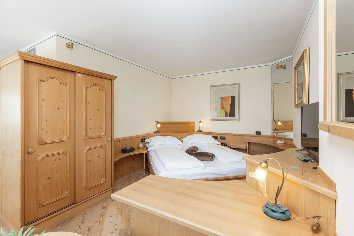 A bedroom with a wooden bed, bedside tables, a wardrobe, and a mirror.