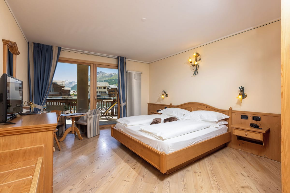 A hotel room with a wooden bed, a desk, and a television.