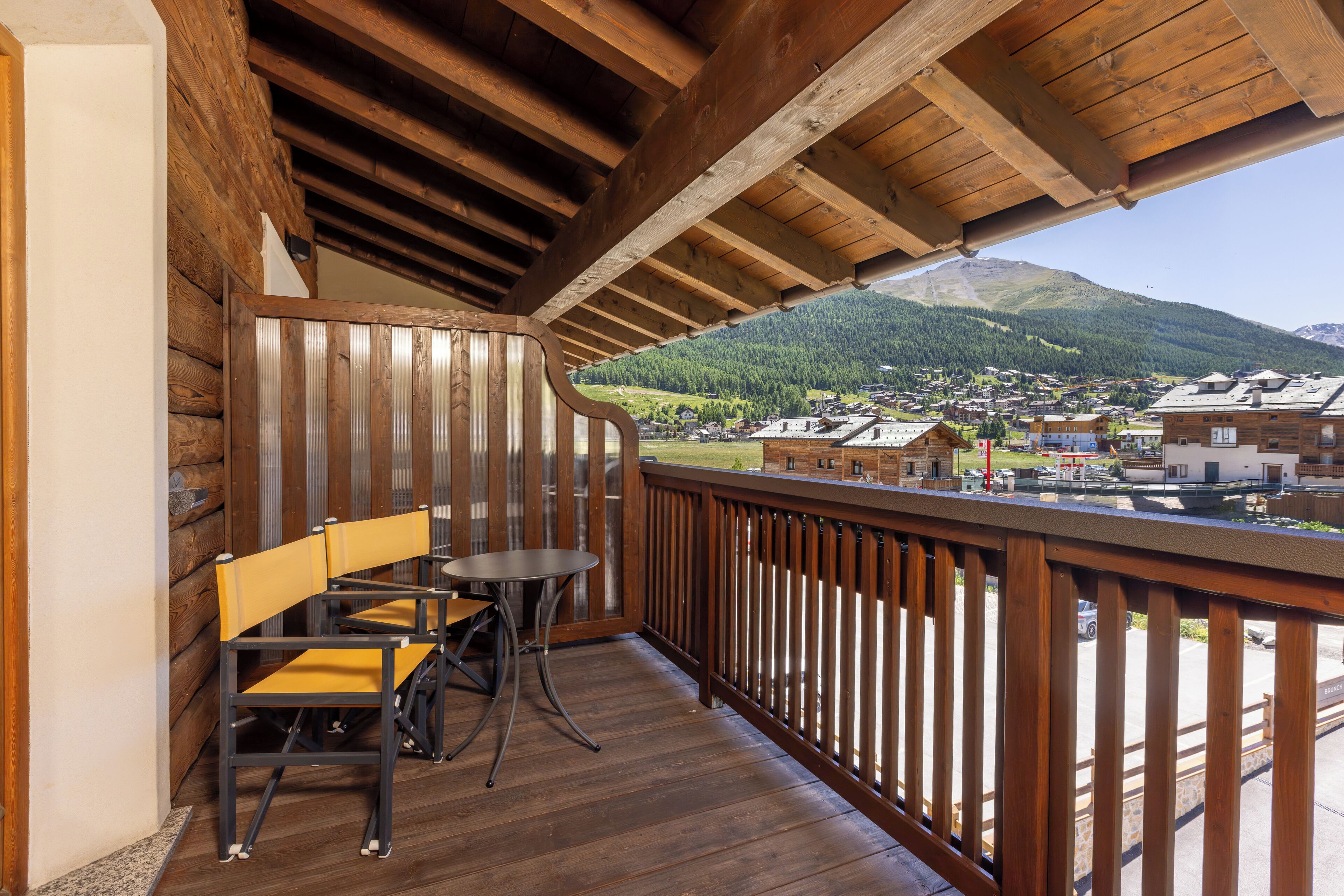 Un balcon en bois offrant une vue sur la ville et les montagnes.