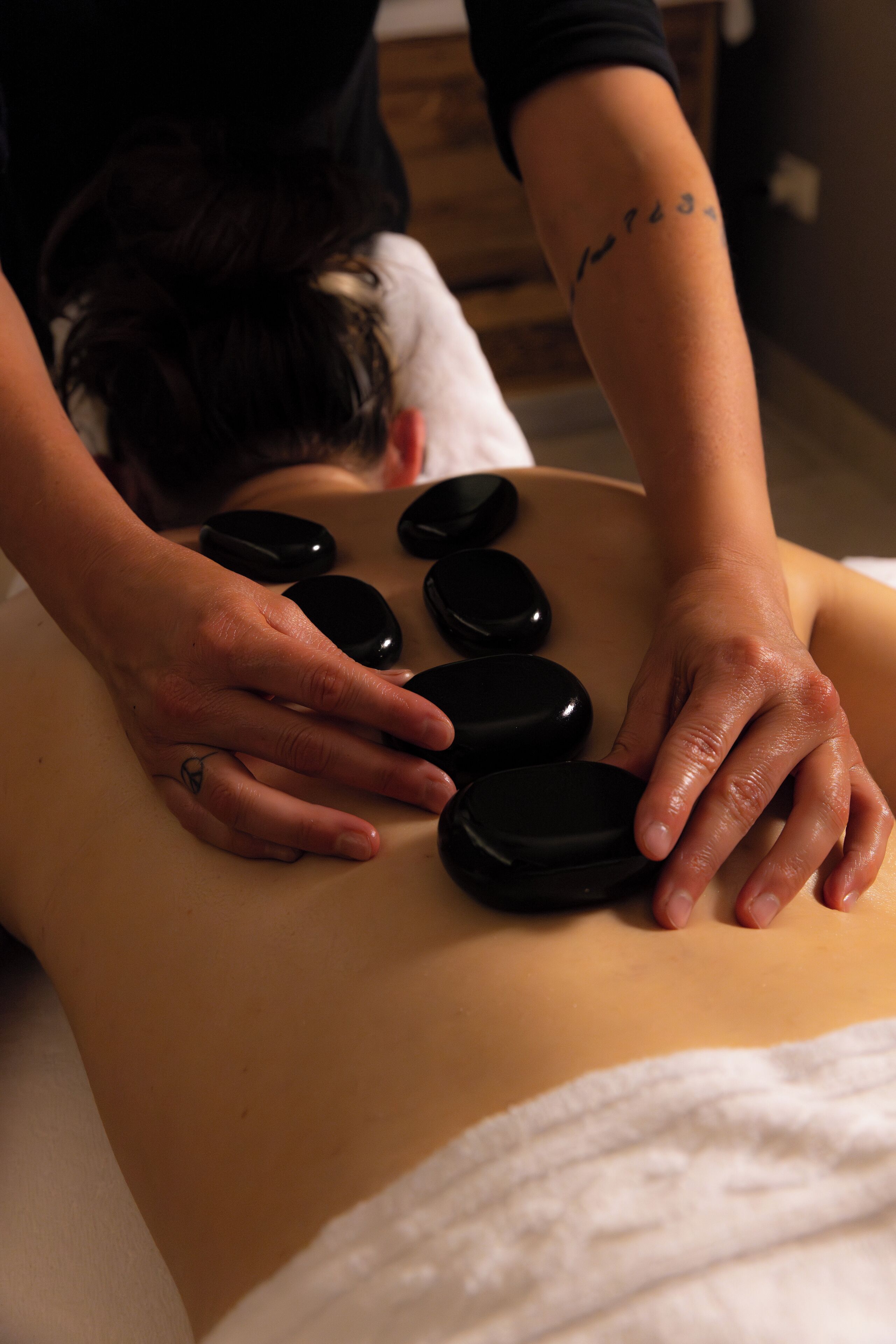 A massage therapy session with a person lying face down on a massage table, receiving pressure from a therapist's hands.