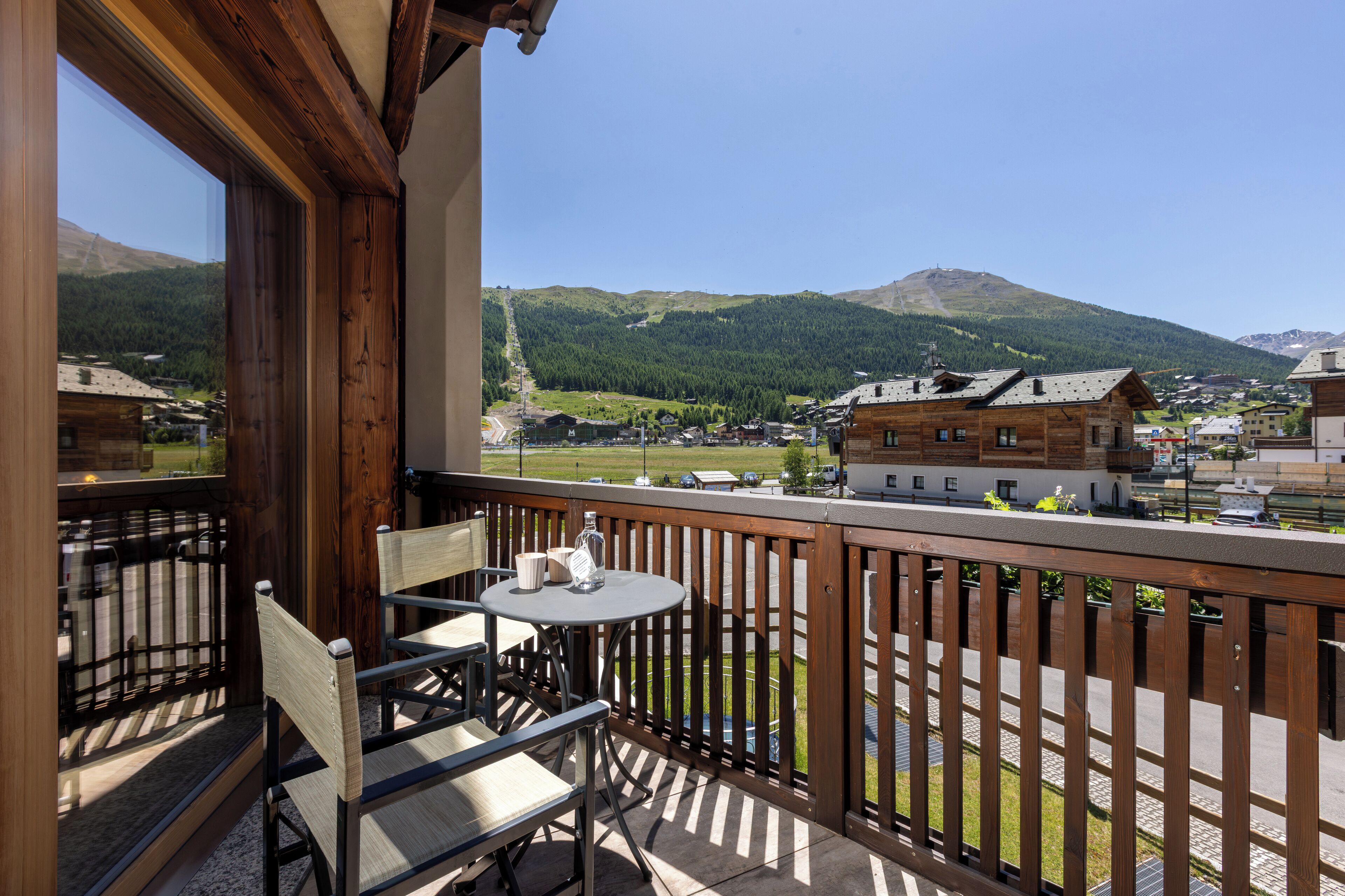 A balcony with a wooden railing, a table, and two chairs.