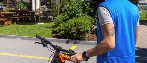 A man standing next to a bicycle in a parking area with a building in the background.