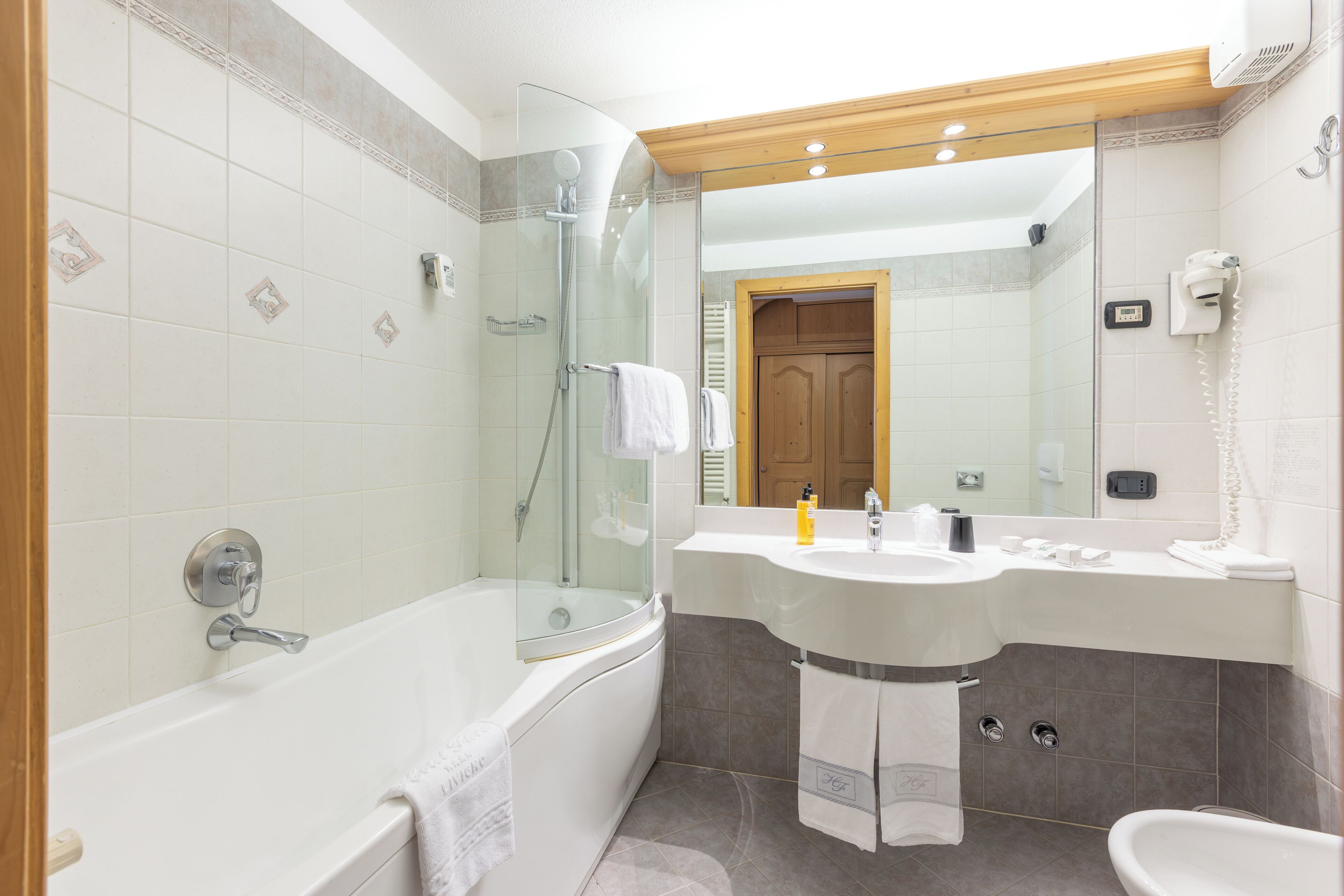 A modern bathroom with a glass-enclosed shower, a freestanding bathtub, a vanity with a sink and mirror, and a separate toilet area.