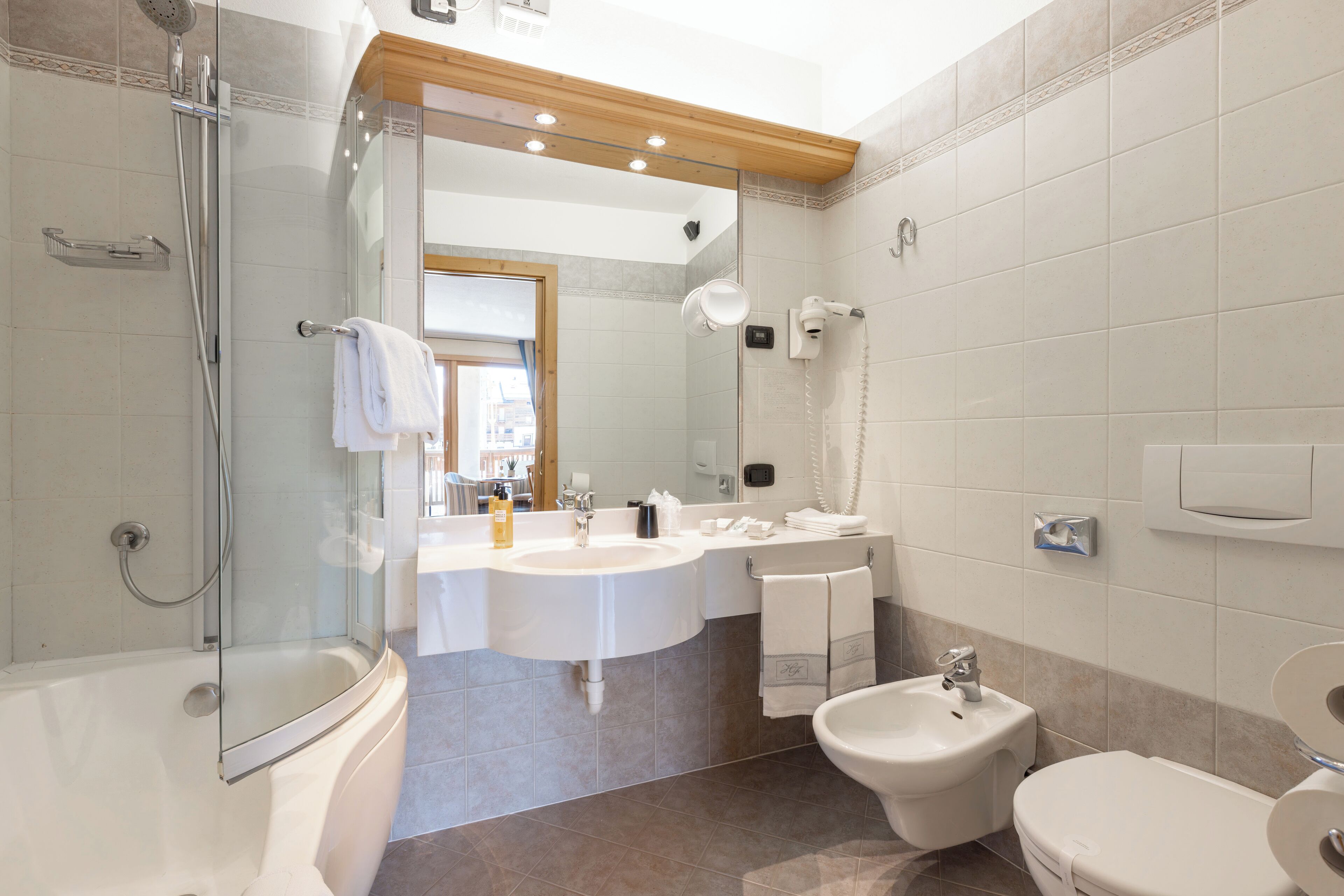 Un bagno moderno con doccia vetrata, doppio lavabo, bidet e WC.