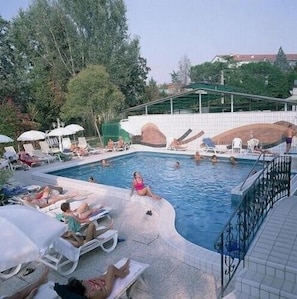 A swimming pool with lounge chairs and umbrellas, surrounded by trees and a building in the background. - Hotel Terme Villa Piave (Abano Terme)