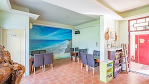 A dining area with a mural of a beach, a red door, and a wooden sculpture. - Hualien Tour B&B (Xincheng)