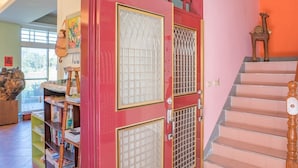 A staircase with a wooden handrail and a red door with glass panels. - Hualien Tour B&B (Xincheng)
