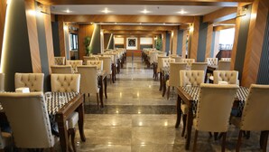 A hotel dining area with rows of tables and chairs, a polished marble floor, and wooden paneling on the walls. - Side Yesiloz Hotel - All inclusive (Manavgat)