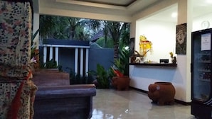 A reception area with a counter, a clock, and a decorative wall. - Palm Garden Bali (Nusa Dua)