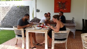 Un espace repas comprenant une table et des chaises, un mur au décor texturé et un tableau abstrait rouge.