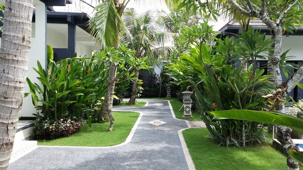 A pathway leading to a building surrounded by lush greenery and a small decorative lantern. - Palm Garden Bali (Nusa Dua)