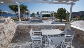 Une terrasse extérieure avec un sol en pierre, des meubles blancs et une vue sur la mer.