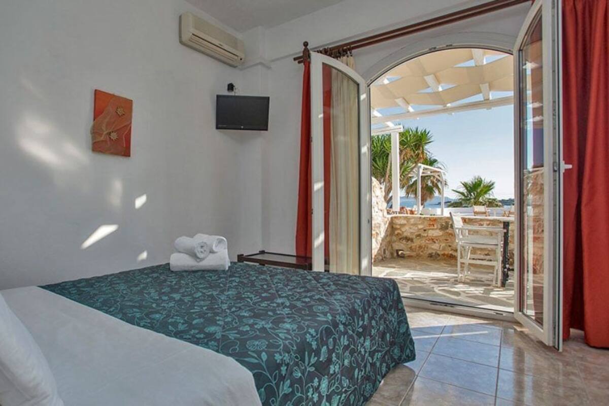 Un dormitorio con cama, televisor y vistas al exterior.