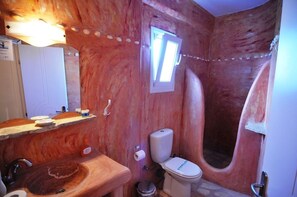 Une salle de bain au décor rustique, comprenant un lavabo en bois, des toilettes et une baignoire.