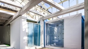 Een modern interieur met grote glazen deuren en een hoog plafond met zichtbare balken.