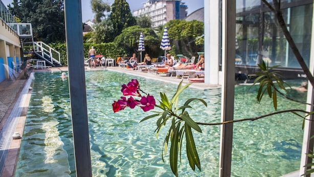 Een zwembad met helder water, omringd door ligbedden en parasols.