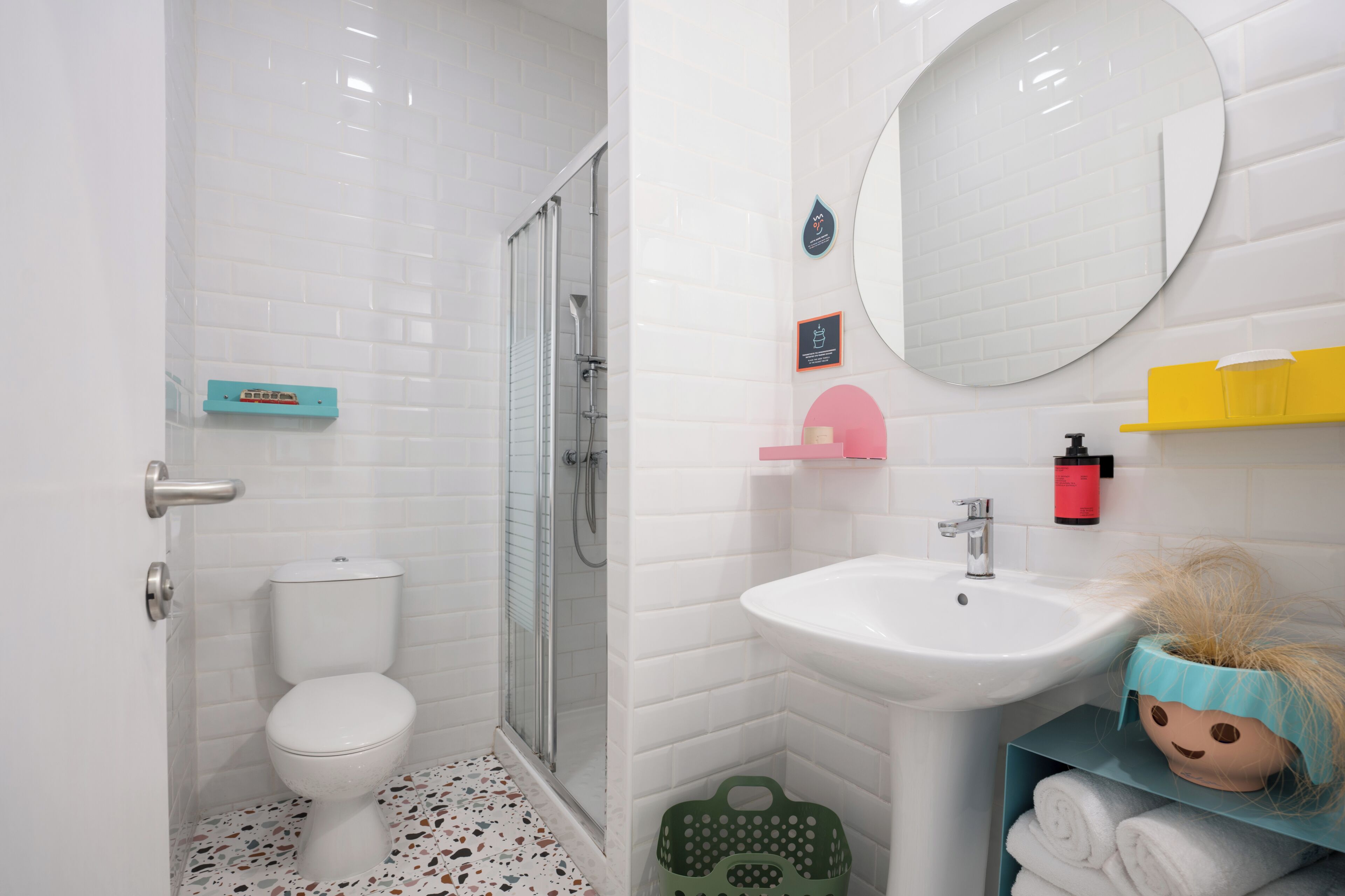 A bathroom with a white toilet, a shower, a sink, and a mirror.