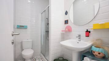 A bathroom with a white toilet, a shower, a sink, and a mirror.