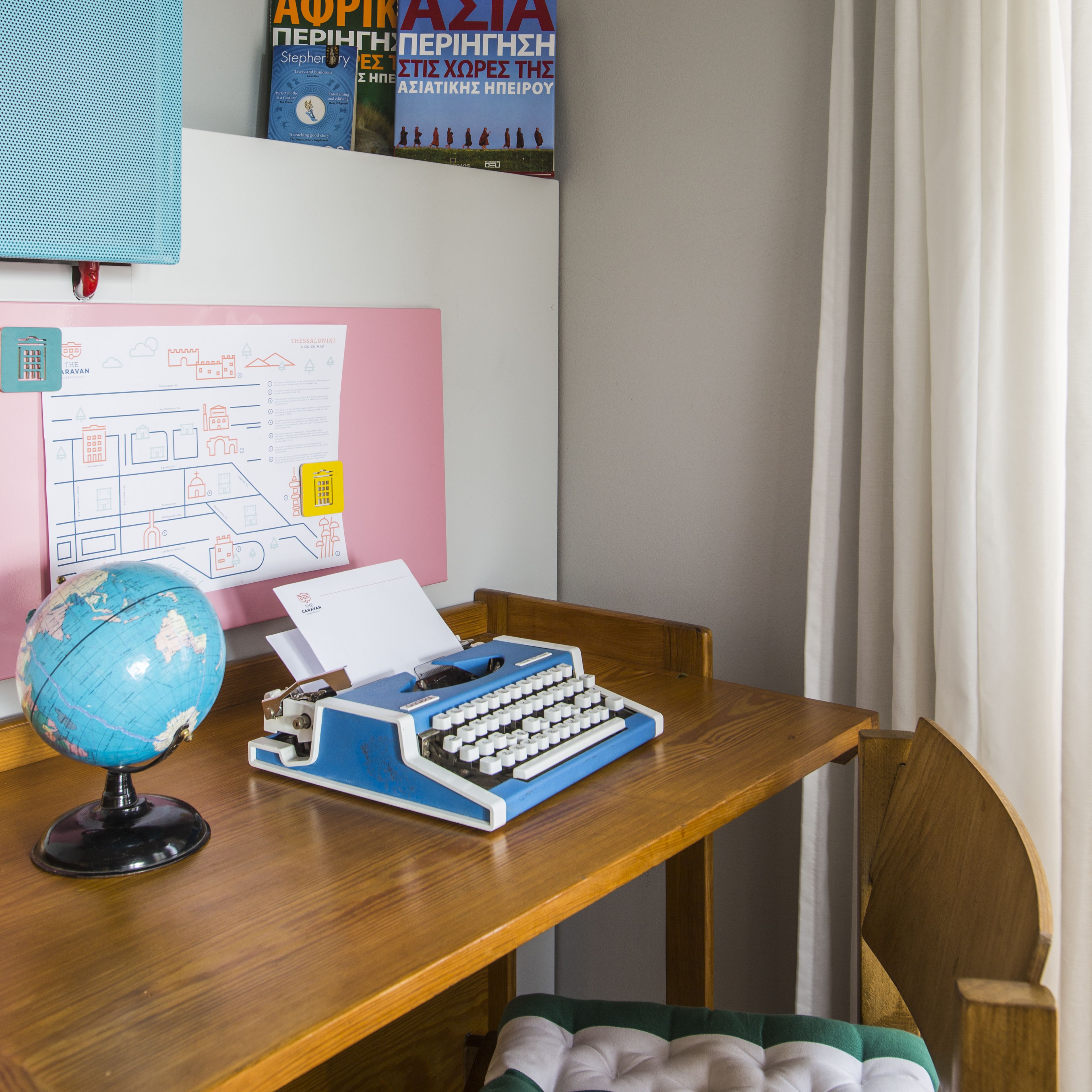 A wooden desk with a globe, a typewriter, and a map.