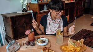 A dining table with a clock, a drink with a straw, a sandwich, and a bowl of chips.