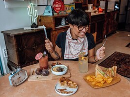 A dining table with a clock, a drink with a straw, a sandwich, and a bowl of chips.