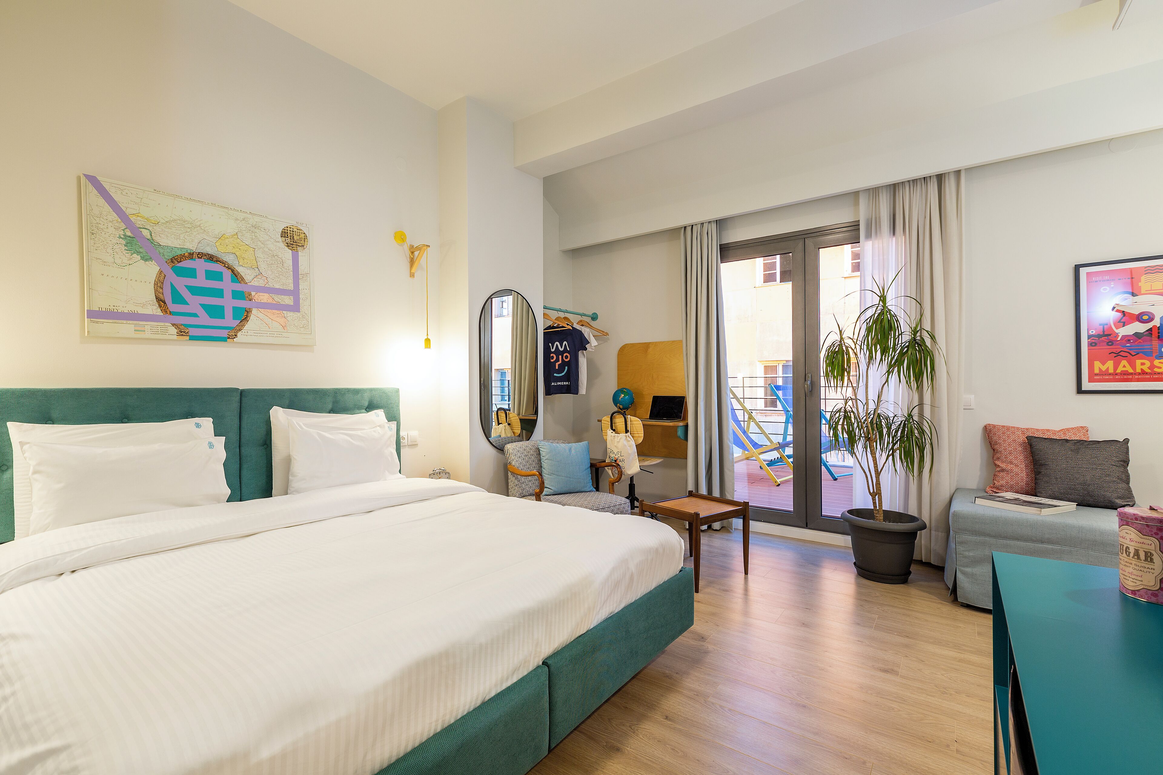 Habitación de hotel con una cama grande, un escritorio, una silla, una planta en maceta y vistas al exterior.