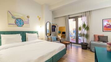 Habitación de hotel con una cama grande, un escritorio, una silla, una planta en maceta y vistas al exterior.