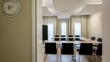 A conference room with a long table, black chairs, and a projector screen.