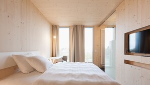 Una habitación de hotel moderna con una cama grande, un escritorio y un televisor en la pared.