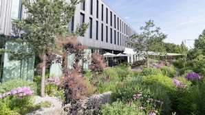 Un edificio moderno con ventanas verticales y un jardín con diversas plantas y flores.