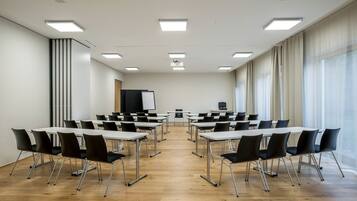 Una sala conferenze con lavagna, proiettore e un'ampia finestra con tende.