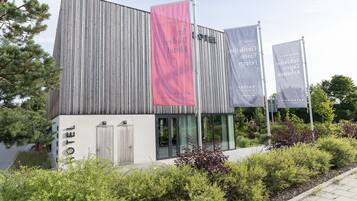 A modern hotel with vertical siding, a prominent red banner, and multiple gray banners.