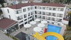 A multi-story hotel with a pool area, outdoor seating, and a water slide. - Park Avrupa Hotel (Kemer)