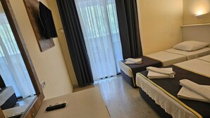 A hotel room with two single beds, a small desk with a remote control, and a window with curtains. - Park Avrupa Hotel (Kemer)