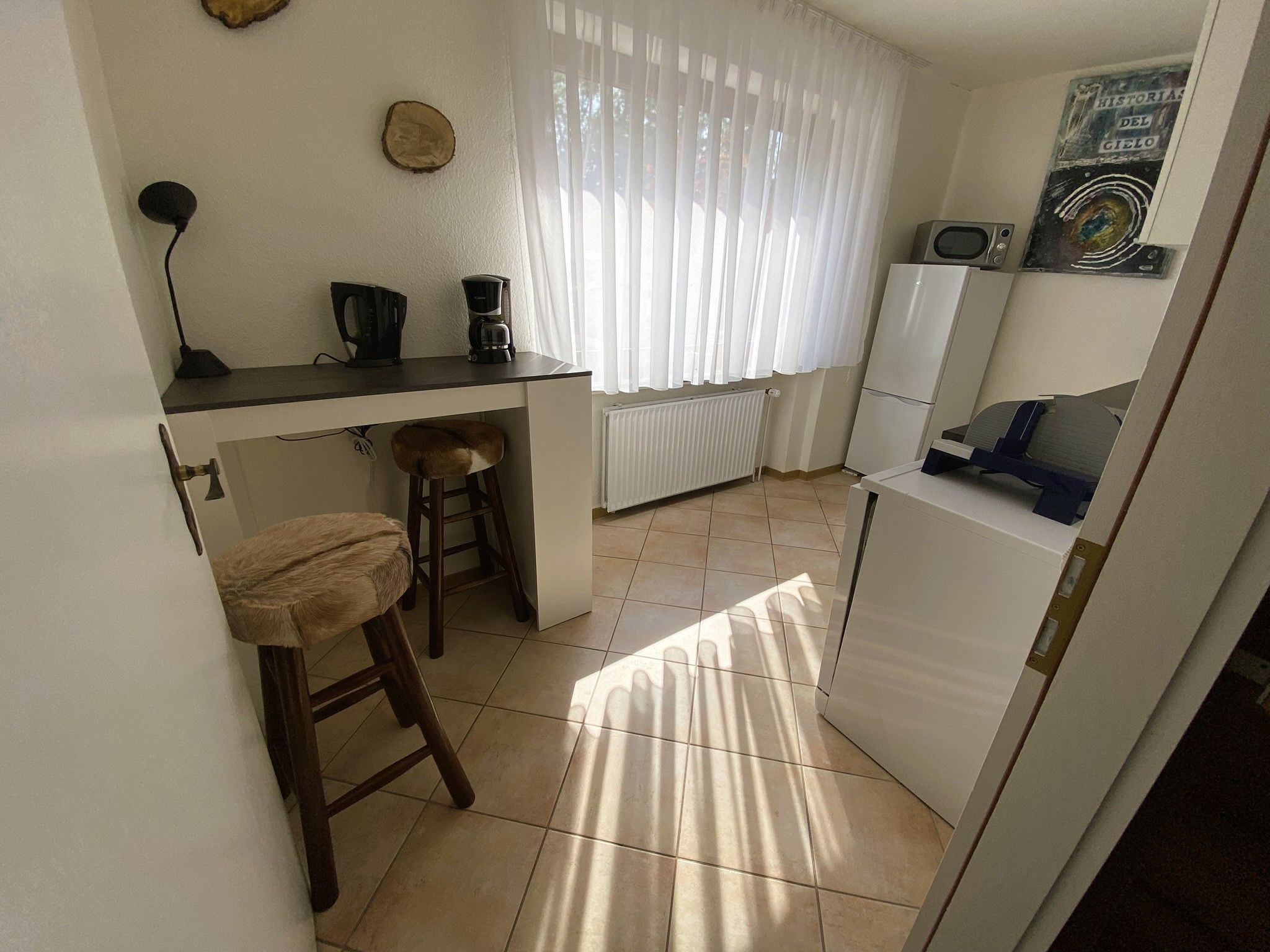 A compact kitchen with a bar area, a coffee maker, a refrigerator, and a microwave.