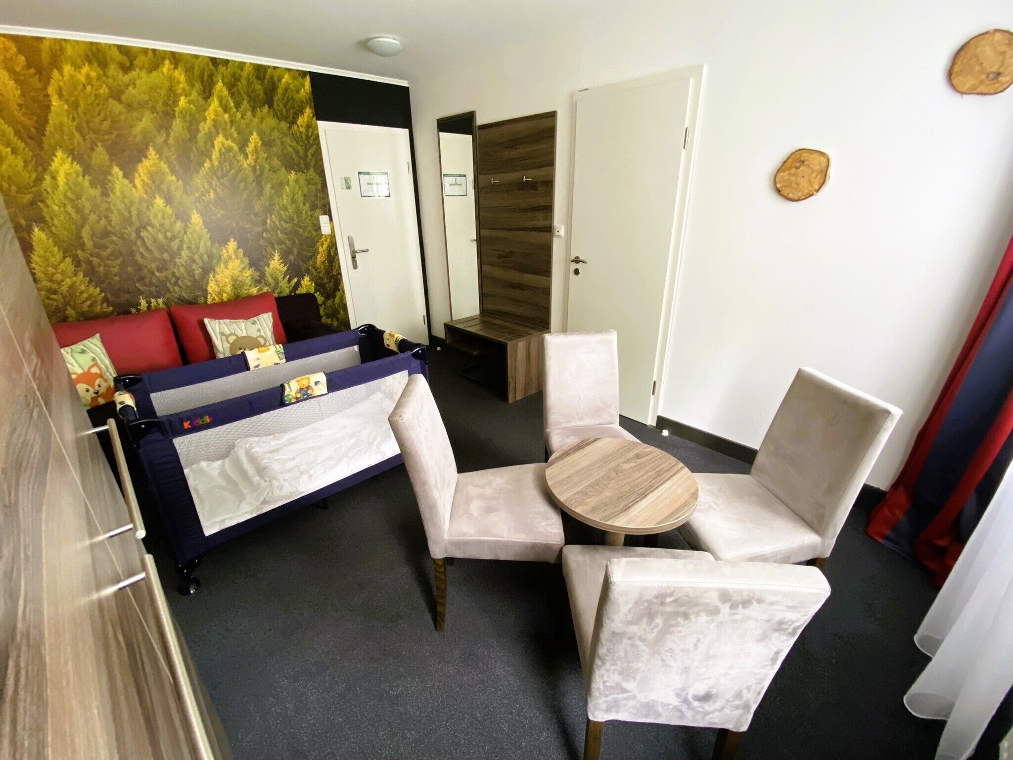 Ein Zimmer mit einem Bett, zwei Stühlen, einem kleinen Tisch und einem Wandgemälde.