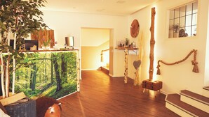 Een moderne woonkamer met een houten vloer, een groot schilderij en een gezellige zithoek.