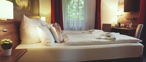 Habitación de hotel con una cama grande, un escritorio, una silla, un televisor y una ventana con cortinas.