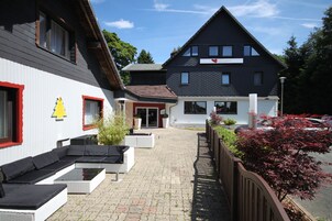 A building with a modern design, featuring a large outdoor seating area with white furniture and a glass table.
