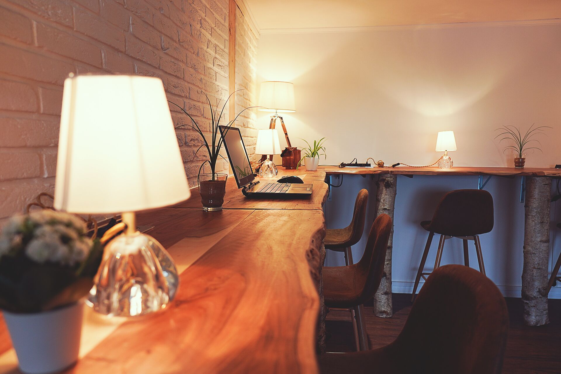 Una habitación acogedora y bien iluminada, con una mesa de madera, sillas, una computadora portátil y una pequeña zona de bar.